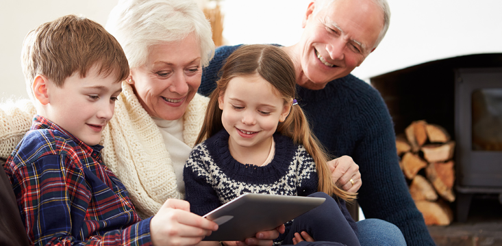 Multigenerational family sitting together, engaging with a tablet in a cozy living room.